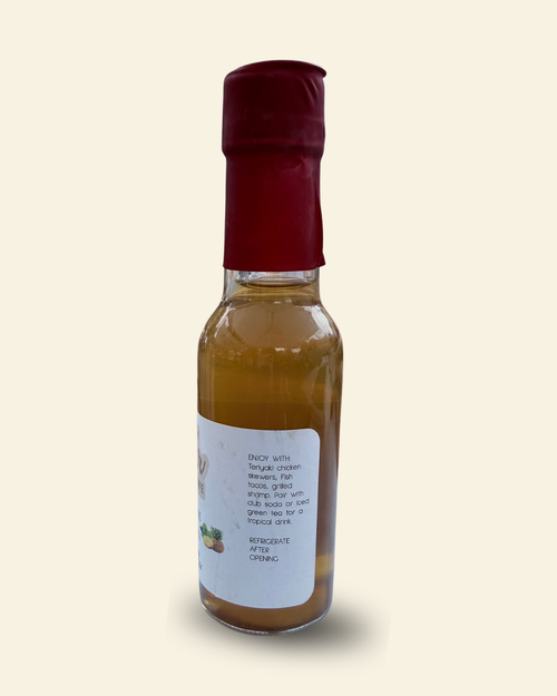 A small glass bottle of Pear Cafe Golden Breeze natural white vinegar with a dark red cap and a white label, set against a solid cream-colored background.