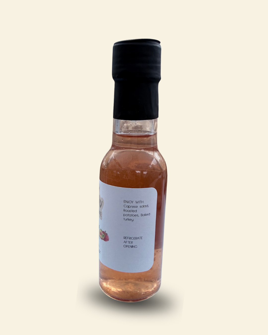 A small glass bottle of Cozy Pear Cafe Nectar & Vine infused white balsamic vinegar, featuring a white label and a black cap, set against a solid cream-colored background.